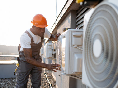 African man in uniform checking air conditioner on plant